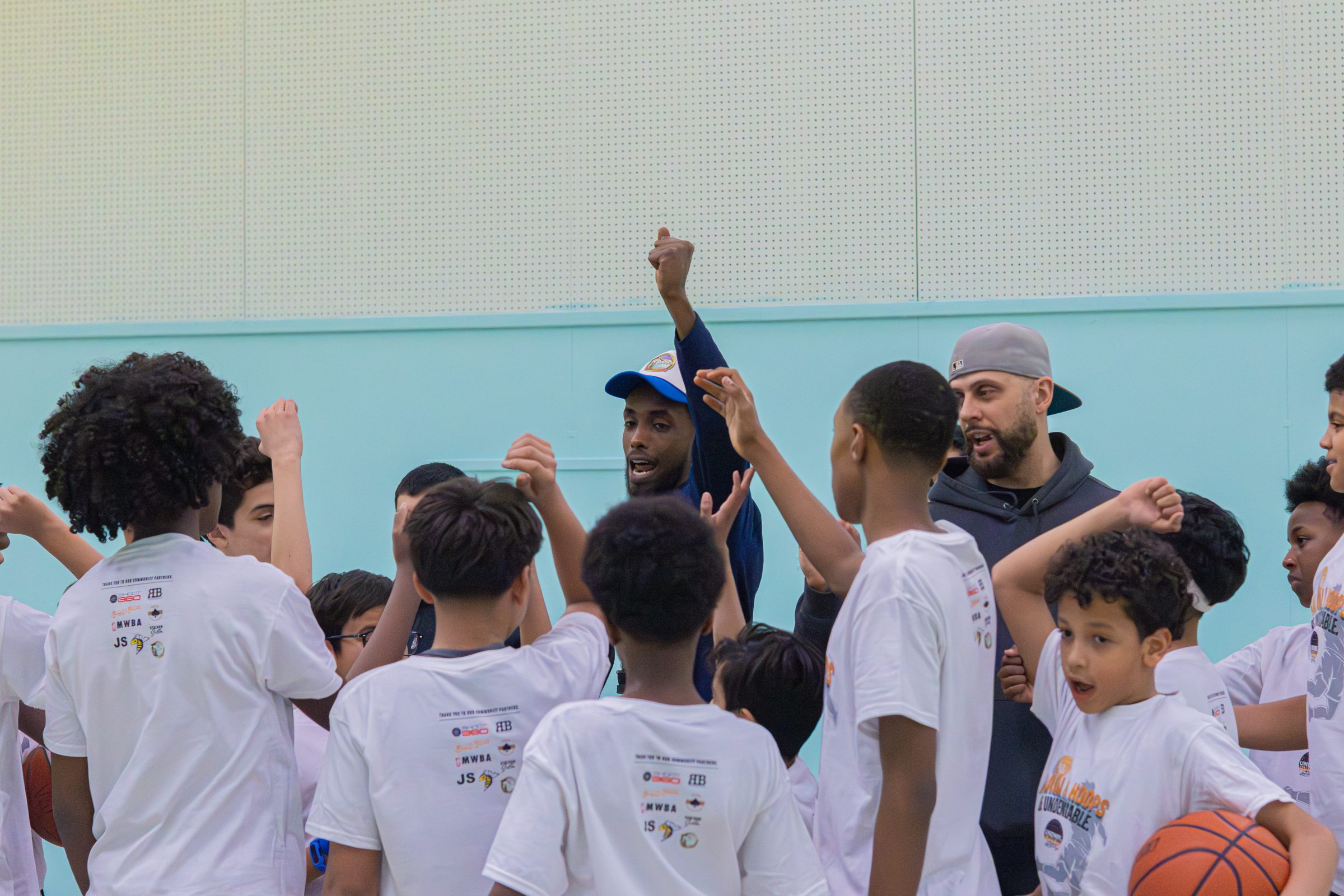 Coaches leading a hands-in huddle with youth players