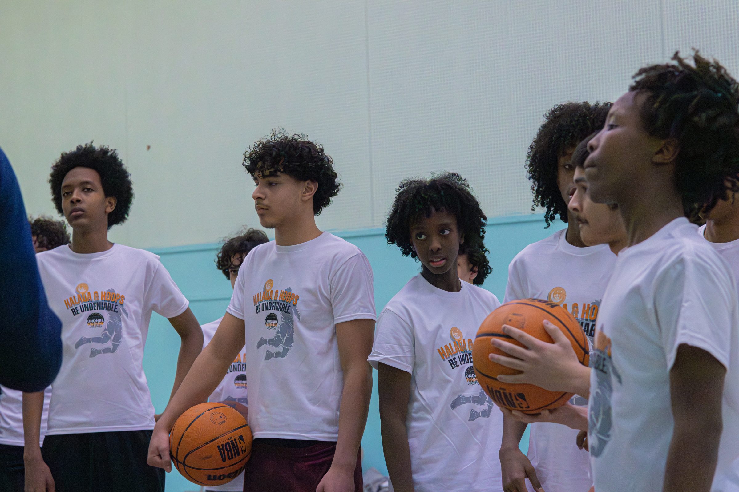 Athletes in Be Undeniable shirts listening during a session